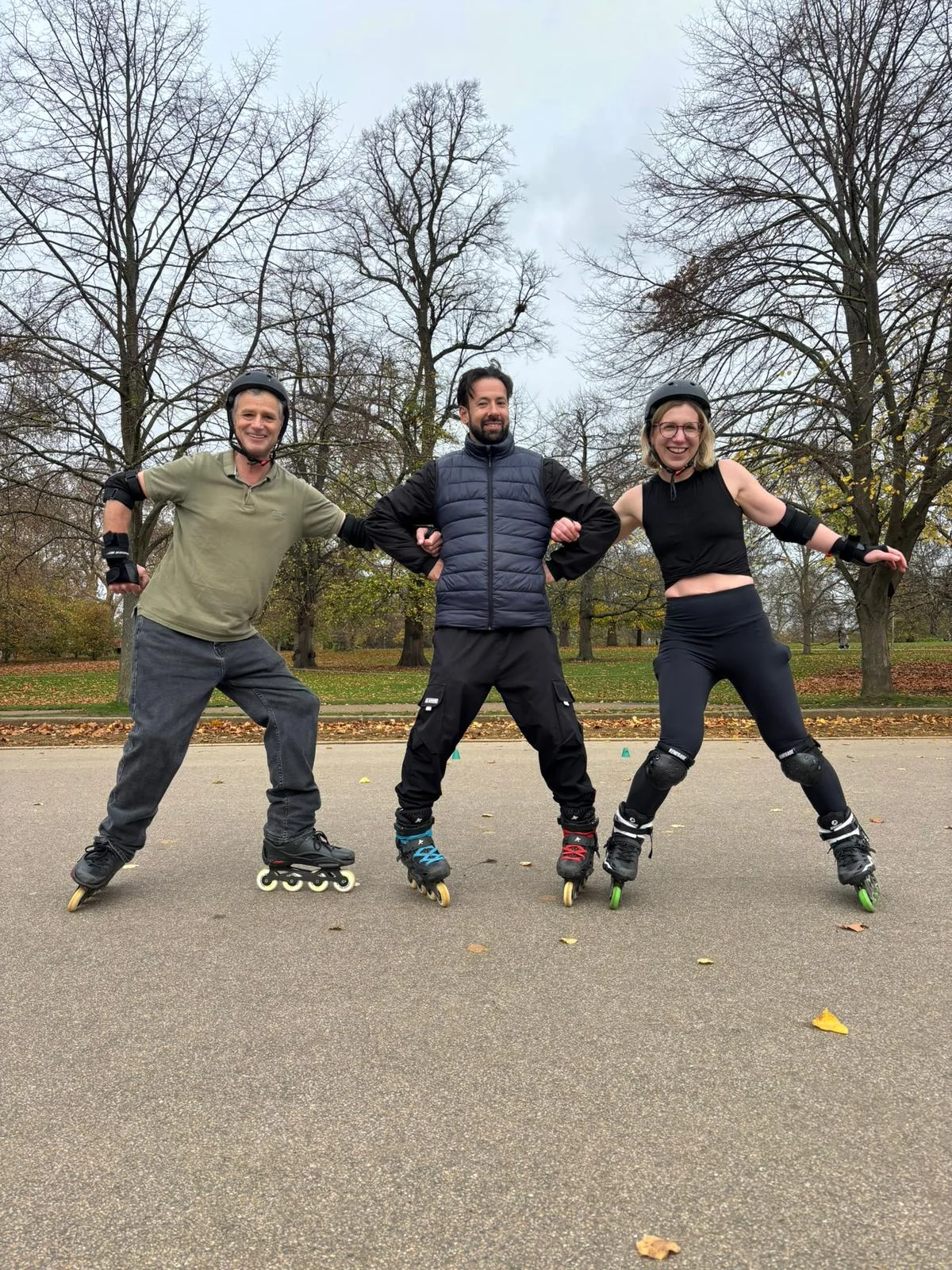 Three skaters smiling and practising balance together in a park