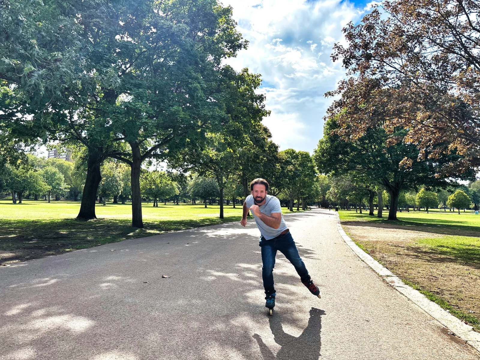 A skater practising one-foot balance on a sunlit park path